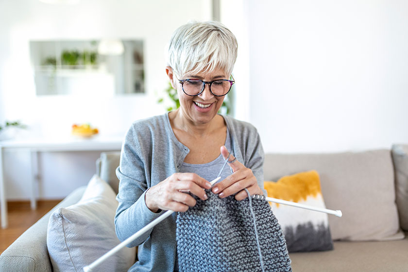 Elderly woman in glasses sit on couch at home