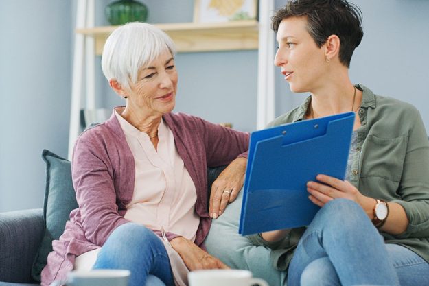 an attractive young healthcare professional sitting with her senior patient