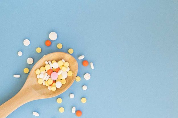 Colorful pills and medicines in wooden spoon