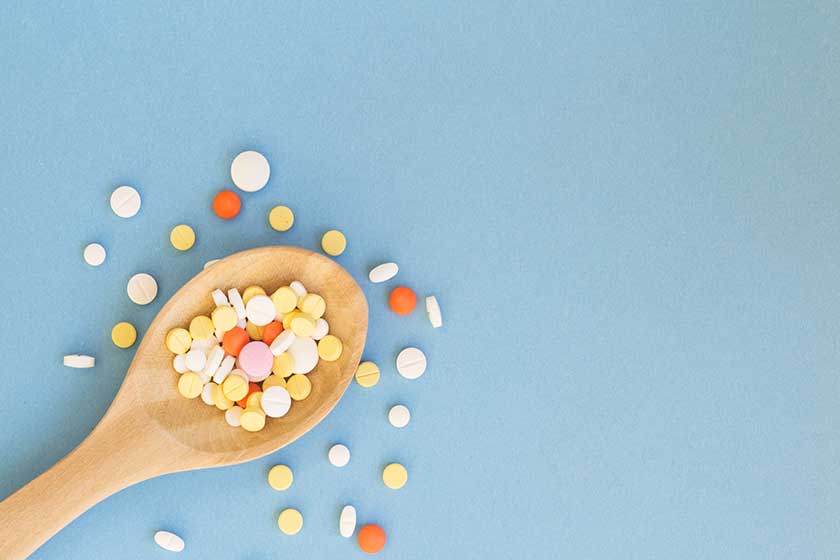 Colorful pills and medicines in wooden spoon
