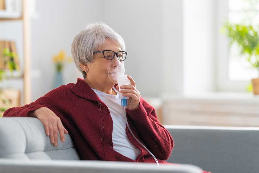 Elderly woman using inhaler for asthma and respiratory diseases at home