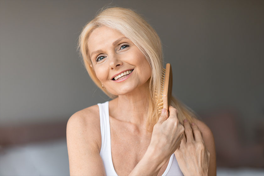 Happy senior european woman combing her hair