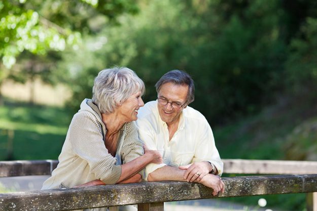 Senior Couple Leaning On Railing At Park
