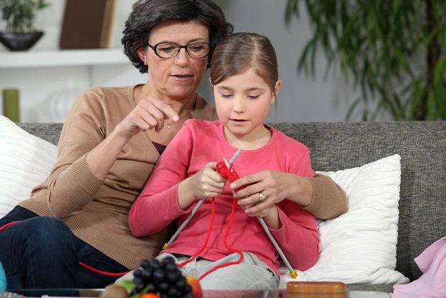 Woman teaching how to knit to little girl Woman teaching how to knit to little girl