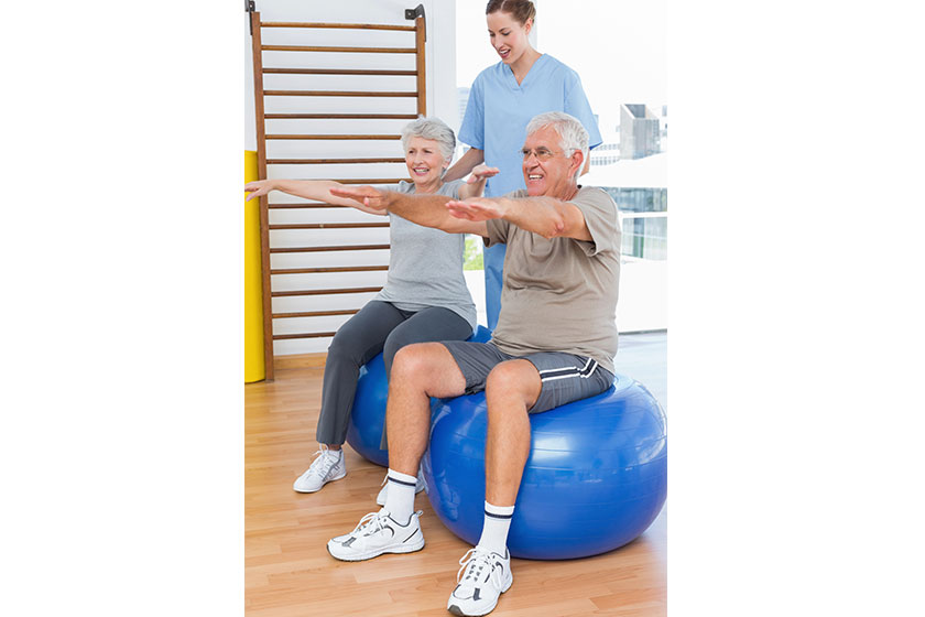 Therapist assisting senior couple with exercises