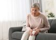 Arthritis symptoms. Woman suffering from pain in knee at home