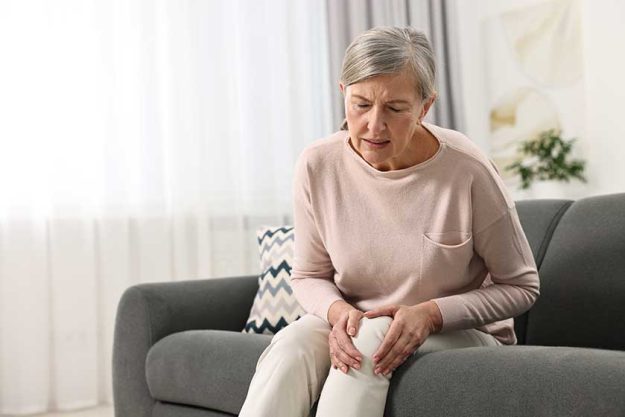 Arthritis symptoms. Woman suffering from pain in knee at home Arthritis symptoms. Woman suffering from pain in knee at home
