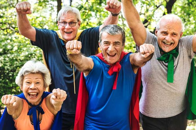 Powerful aged people wearing superhero costumes coats in green summer park Powerful aged people wearing superhero costumes coats in green summer park
