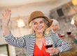 Joyful woman in a brown hat holding a glass of wine