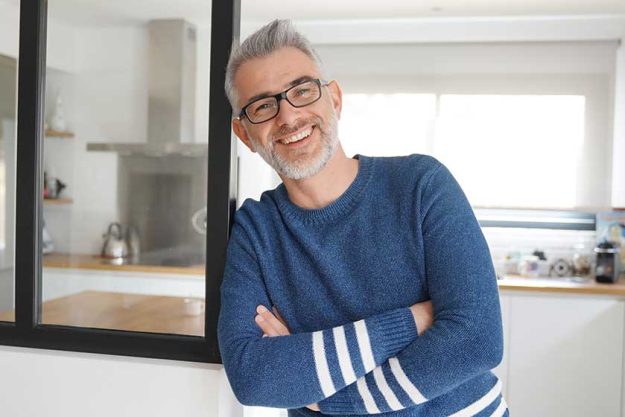 Man leaning and smiling at home in modern kitchen