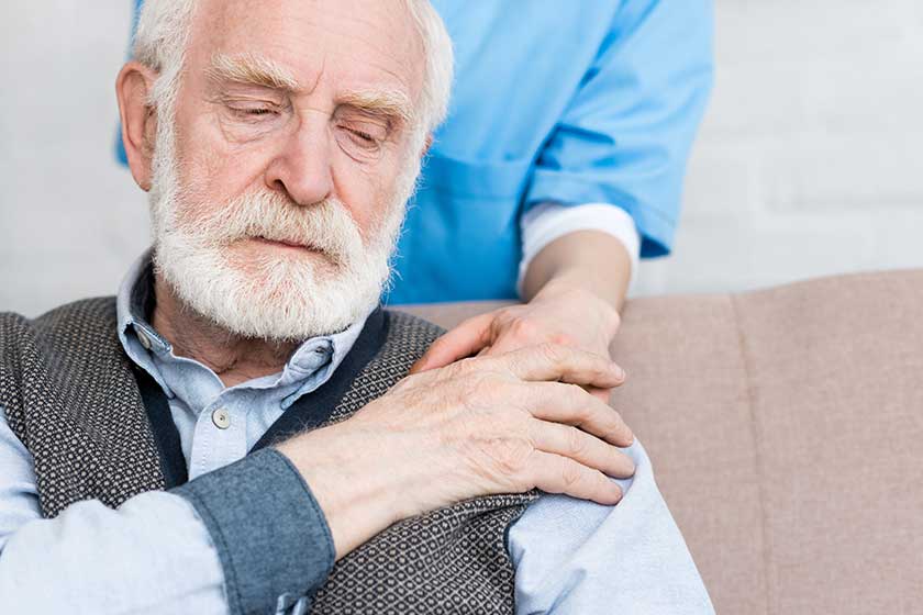 Nurse putting hand on sad senior man