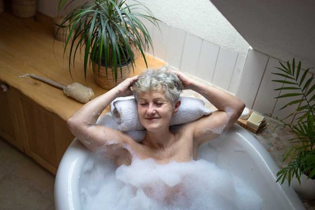 Top view of contented senior woman lying in bath tub at home, eyes closed. Top view of contented senior woman lying in bath tub at home, eyes closed.