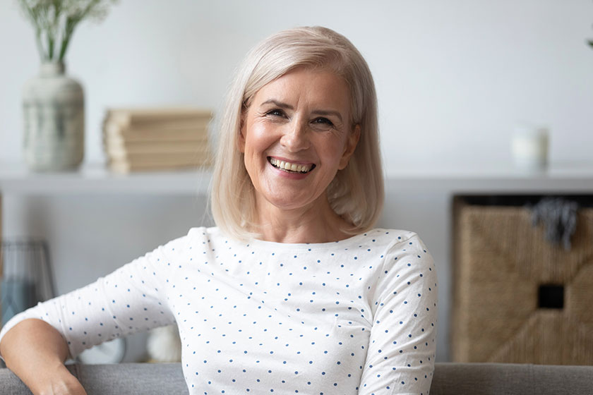 Headshot aged woman smiling sitting on couch