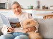 Senior woman with Pomeranian dog reading magazine